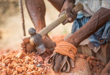 Worker is using a small hammer to destroy old bricks that will be used for roadworks