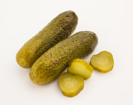 Two whole cucumber pickles and slices isolated on white
