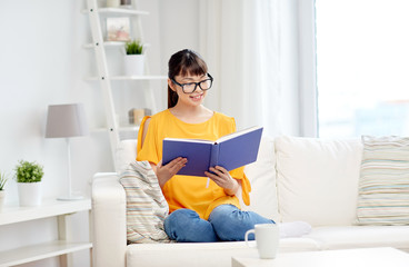smiling young asian woman reading book at home