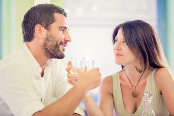Young romantic couple drink to each other at restaurant