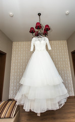 The perfect wedding dress on a hanger in room of  bride 