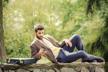 Naklejka na ściany i meble Young business man relaxing using smartphone outdoor in nature