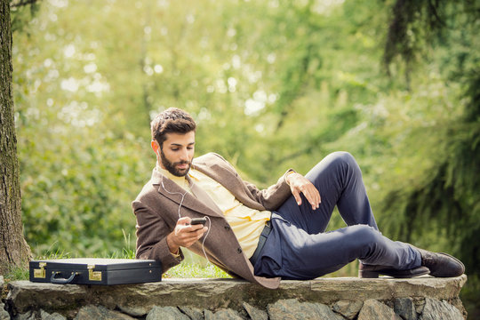 Young business man relaxing using smartphone outdoor in nature