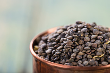 Raw lentils in bowl on a blue wooden table