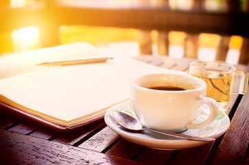 workplace, coffee cup on wooden table - over sunlight [blur and select focus background]