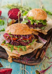 Tasty beef burgers on wooden table.