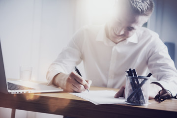 Close up of successful smiling businessman signing contract at his office
