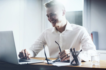 Happy smiling businessman working at his office with laptop