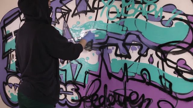 Video shot of a young girl paints a graffiti on the wall
