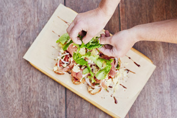 Chef's hands adding rocket to a gourmet bruschetta