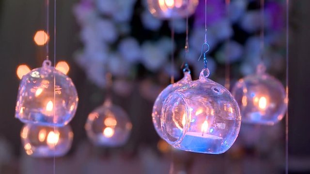 Hung  candles and flowers in the background.The interior of the hall pn the party , celebration. Hanging lighting  candles . candle loop