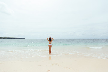 Fototapeta na wymiar Beautiful girl in swimsuit walking along the beach.back view