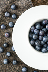 blueberries in a white cup on a brown cloth