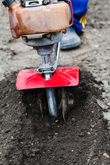 Fototapeta premium farmer plows field by tiller in spring