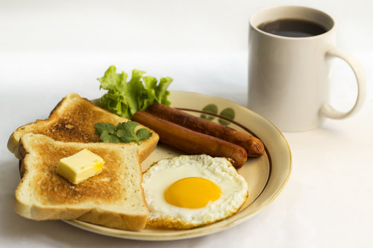 healthy breakfast fried egg yellow yolk, toast bread, sausage, vegetable in morning,  delicious sandwich diet lunch with coffee