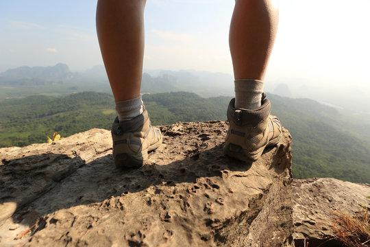 young woman hiker legs on  mountain peak rock