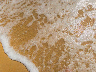 Waves wash over golden sand on beach