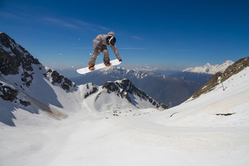 Naklejka na ściany i meble Snowboard rider jumping on mountains. Extreme snowboard freeride.