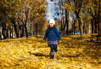 Little girl playing in autumn park