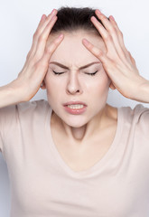 Young thin pale woman suffering from a headache. She's exhausted and tired. She feels hard pain. Strong emotions, despair, sadness, hopelessness, lack of understanding, anguish. Facial expressions.