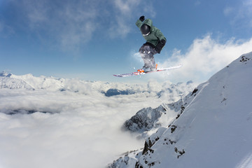 Naklejka na ściany i meble Ski rider jumping on mountains. Extreme ski freeride.