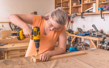 Female woodworker drilling into board