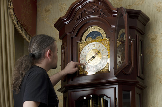 man adjusts analog old clocks