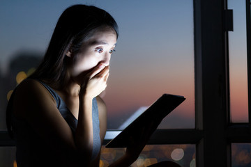 Woman reading a shocked news on tablet pc