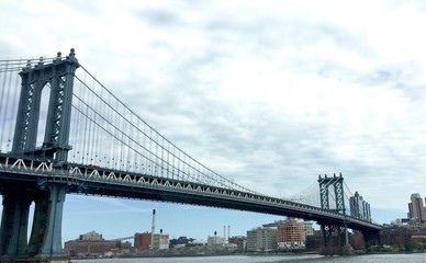 Fototapeta na wymiar Manhattan bridge and the city under cloudy sky, New York