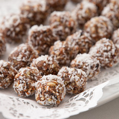 White plate full of delicious raw protein balls. Healthy sweets for sport people. Homemade dessert. Raw sweets made of nuts, coconut, dates and cacao