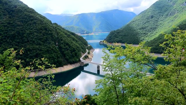 Красивое горное ущелье в Черногории. Величественные горы, узкий серпантин дорог, длинный мост, горное озеро с чистейшей водой. Девственная природа и прекрасная экология.