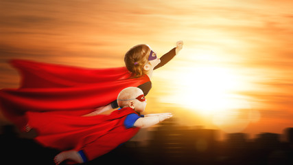 Fototapeta na wymiar children superheroes flying across sunset sky
