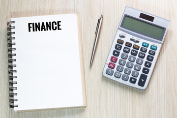 Top view of Finance wording on notebook with calculator and pen