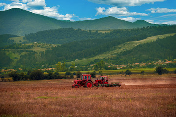 farmer working the fields with tractor and plow in summer