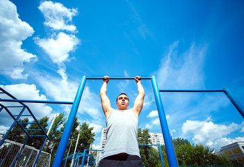 Muscular man doing pull-ups on horizontal bar