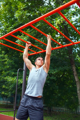 Fototapeta premium Muscular man doing pull-ups on horizontal bar