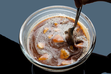 Stirring sliced garlic in tomato sauce in glass bowl