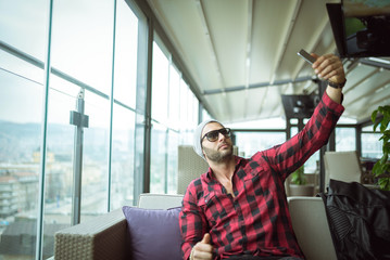 Young fit man taking selfie in cafe