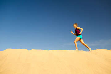 Young woman running on sand desert dunes
