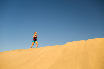 Young woman running on sand desert dunes