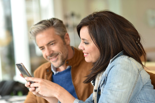 Mature couple using smartphone in coffee shop