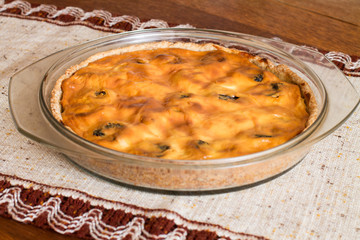 Cake with cottage cheese and prunes in glass brazier on wood table.