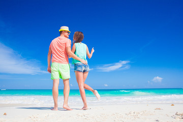 Fototapeta na wymiar back view of couple in bright clothes having fun at tropical beach