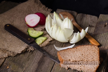 Rye bread, vegetables and knife on an old table