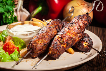 Grilled shish kebab served with fried chips and salad