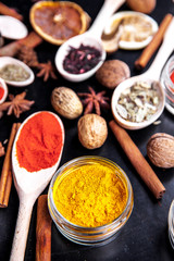 wooden spoons with spices on black background