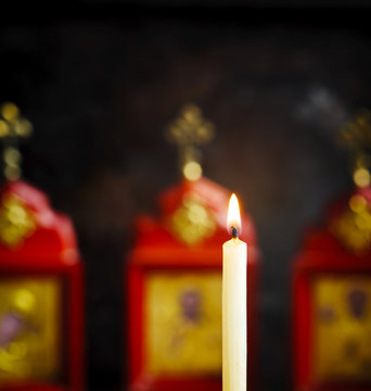 Burning candle against the background of the Christian icons