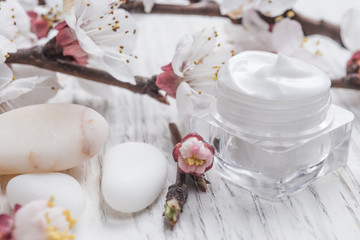 Obraz na płótnie Canvas Facial cream with beauty cherry blossoms and white pebblestone 