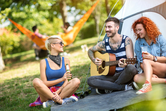 Young guy play guitar while girls enjoy in music and beer
