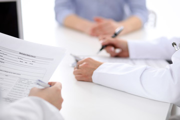 Close-up of a female doctor holding application form while consulting patient